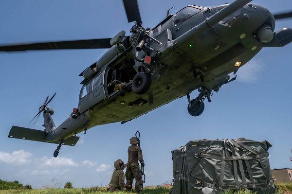Staff Sgt. Paul Bartholdson and Tech. Sgt. Nathan Edwards, 920th Logistics Readiness Squadron rescue riggers, prepare to attach a reach pendent underneath a HH-60G Pave Hawk during sling load training at Patrick Space Force Base, Fla., July 25, 2023. A sling load is used to transport various types of cargo to remote locations or to expedite shipments into austere environments while suspended beneath the HH-60G. (U.S. Air Force photo by Staff Sgt. Darius Sostre-Miroir) 