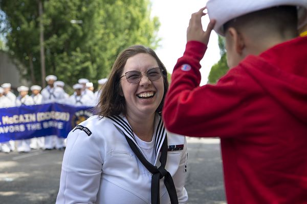 Logistics Specialist 2nd Class Autumn Hoadley, assigned to USS Kansas City (LCS 22), shares her cover with a child at the annual Rose Festival Parade during Portland Fleet Week in Portland, Oregon, June 10, 2023. Portland Fleet Week is a time-honored celebration of the sea services and provides an opportunity for the citizens of Oregon to meet Sailors, Marines and Coast Guardsmen, as well as witness firsthand the latest capabilities of today's maritime services. (U.S. Navy photo by Mass Communication Specialist Seaman Sophia H. Bumps)