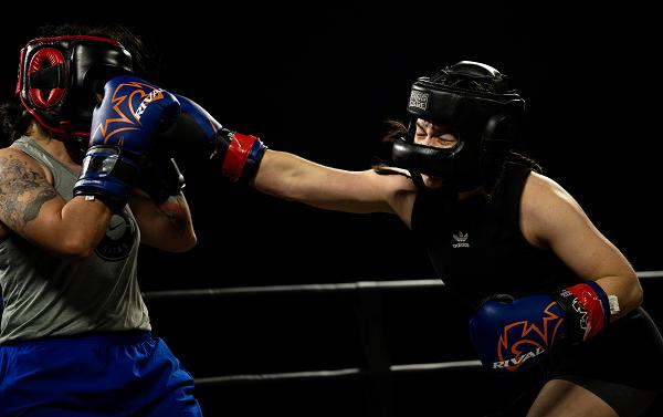 U.S. Air Force Senior Airman Lian Espinoza, assigned to the 379th Expeditionary Force Support Squadron, delivers a blow to her opponent during the Rumble in the Deid II boxing event, March 9, 2024, at Al Udeid Air Base, Qatar. Events like these cultivate a warrior mindset and reinforce Al Udeid AB’s priority of developing warfighters. (U.S. Air Force photo by Tech. Sgt. Alexander Cook) 