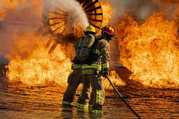 Airman 1st Class Kyle Datu and Staff Sgt. Matt Trevizo, 99th Civil Engineering Squadron fire protection specialists, extinguish a fire during an aircraft live fire training exercise at Nellis Air Force Base, Nev., Oct. 12, 2023. Propane ignitors are built in multiple positions throughout and around the training fuselage, providing firefighters with a realistic training environment. (U.S. Air Force photo by Senior Airman Zachary Rufus)  
