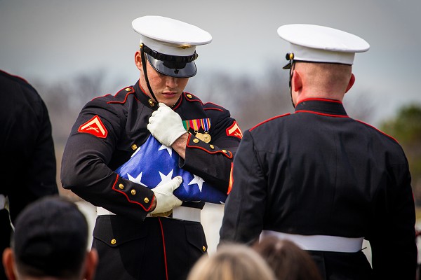 Lance Cpl. Justin Shevlin, Body Bearer, Marine Barracks Washington, prepares the U.S. flag during a funeral for repatriated Marine, Cpl. Thomas H. Cooper, at Arlington National Cemetery, Arlington, Va., March 10, 2022. Cooper, 22, of Chattanooga, Tennessee, was a member of Company A, 2nd Amphibious Tractor Battalion, 2nd Marine Division, which landed against stiff Japanese resistance on the small island of Betio in the Tarawa Atoll of the Gilbert Islands during World War II, and was killed in action. (U.S. Marine Corps photo by Cpl. Tanner D. Lambert)