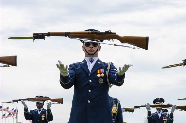 Airman 1st Class Stephen Souza of the U.S. Air Force Honor Guard Drill Team tosses his rifle during a performance at the Joint Services Drill Exhibition, April 14, 2023, at the Washington Monument in Washington, D.C. The team is an elite unit of 25 Airmen who train, on average, five days a week for eight to 10 hours per day to obtain their level of mastery. (U.S. Air Force photo by Kristen Wong) 