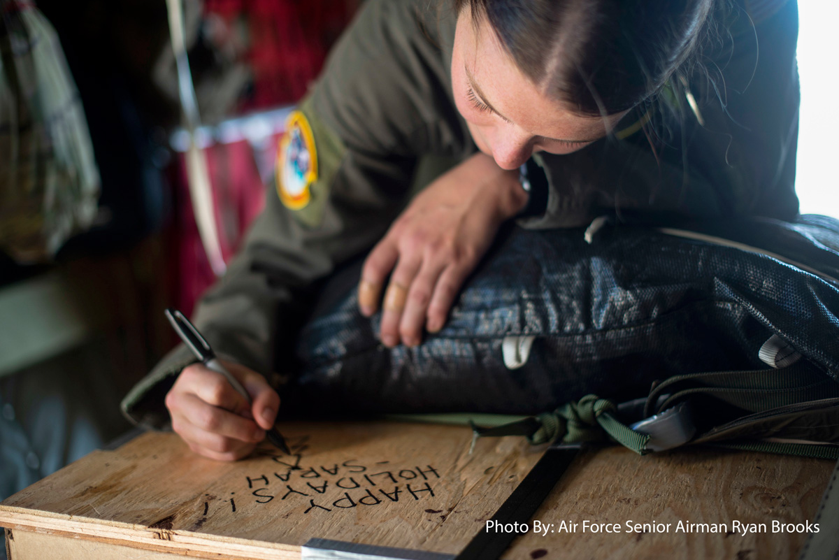 Guam, Dec. 10, 2019 -  Air Force Staff Sgt. Sarah Meadows writes a holiday greeting on a box of humanitarian aid at Andersen Air Force Base, before delivering it as part of Operation Christmas Drop. The annual operation provides donated goods to islanders throughout Micronesia.     Attachments area