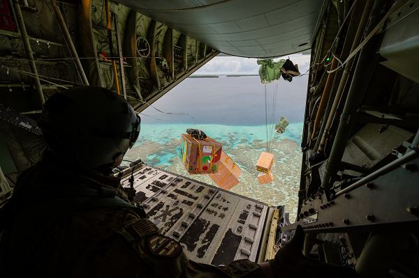 U.S. Air Force Senior Airman Blake Janssen, a 36th Airlift Squadron instructor loadmaster at Yokota Air Base, Japan, watches the release of four low-cost, low-altitude airdrop bundles containing humanitarian-type goods over Lukunor, Micronesia, Dec. 8, 2024, in support of Operation Christmas Drop. Operation Christmas Drop is the longest-running humanitarian airlift operation in the world, conducted annually by the U.S. Air Force in collaboration with allied nations and local partners. It started in 1952 and takes place in December, focusing on delivering essential supplies and holiday gifts to remote islands in the Pacific Ocean. (U.S. Air Force photo by Senior Airman Natalie Doan) 