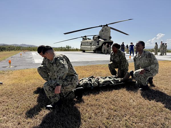 Hospitalman Alex Hall, Hospitalman Jacob Riveracalvo, Hospital Corpsman 3rd Class Keyanna Glenn, and Hospitalman Ashley Mucheru practice litter-bearing during casualty evacuation (CASEVAC) training at U.S. Naval Hospital Guantanamo Bay. U.S. Navy Medicine Readiness and Training Command Guantanamo Bay conducted the training to enhance warfighter-focused medical readiness. Sailors practiced loading and unloading a litter on and off a CH-47 Chinook helicopter, first with rotors disengaged to build familiarity, then with rotors engaged to add realism. The training emphasized clear communication, teamwork, and physical endurance to ensure medical personnel are prepared for casualty evacuation operations in any environment. (U.S. Navy photo by Emily McCamy)                                         