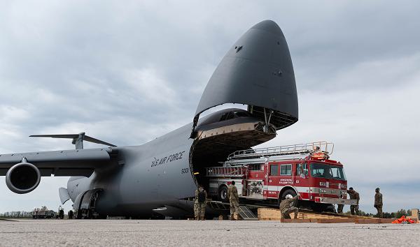 U.S. Air Force Airmen from the 709th Airlift Squadron and the 512th Aircraft Maintenance Squadron load a Pierce Arrow Telesquirt fire truck onto a C-5M Super Galaxy at Scott Air Force Base, Ill., April 9, 2025. Weighing approximately 31,000 to 33,000 pounds without water, the fire truck’s size and weight required careful coordination and precision handling during the loading process. The fire truck was donated by a Non-Governmental Organization as part of the Denton Humanitarian Assistance Program, which provides transportation of humanitarian goods to countries in need. (U.S. Air Force photo by Airman 1st Class Devin Morgan) 