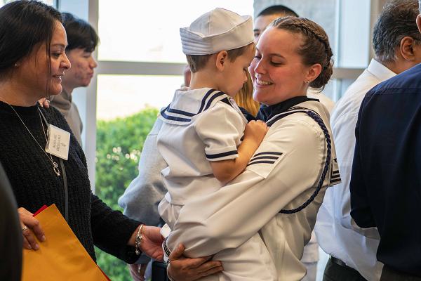250508-N-KL637-1631 (May 8, 2025) -- Seaman Kyra Brinsfield is greeted by family after Recruit Training Command's Pass-In-Review in Midway Ceremonial Drill Hall May 8, 2025. More than 40,000 recruits train annually at the Navy's only boot camp. (U.S. Navy photo by Mass Communication 2nd Class Stuart Posada)