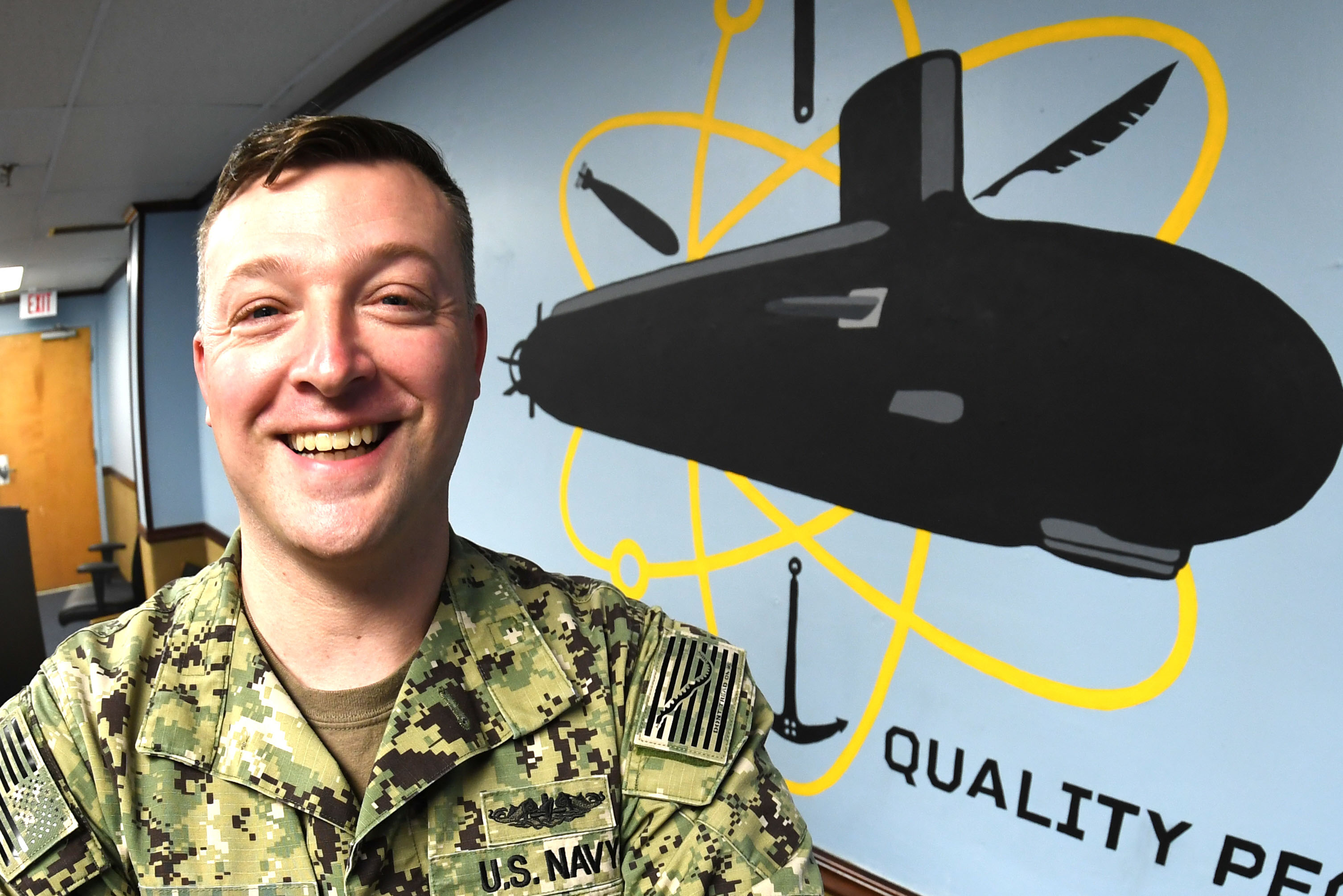210224-N-GR655-013 GROTON, Conn. (February 24, 2021) – Petty Officer 1st Class Jamie Pearson, a Machinist’s Mate (Auxiliary) assigned to Naval Submarine Support Facility New London, stands in front of a mural he painted for his command’s conference room. Pearson has been moonlighting as an artist on and off base in the Groton community since 2014. (U.S. Navy photo by Chief Petty Officer Joshua Karsten/RELEASED)