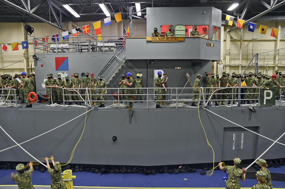 GREAT LAKES, Ill. (July 13, 2021) – Naval Reserve Officers Training Corps (NROTC) New Student Indoctrination (NSI) midshipman candidates practice line-handling procedures on the USS Marlinespike Seamanship Trainer at Recruit Training Command (RTC) as part of NSI, July 13. Upon completion of NSI, the candidates will start their freshman year of the NROTC program at colleges and universities nationwide this fall. NSI is a three-week indoctrination program hosted at RTC, which provides midshipmen with a common military training orientation. NSI provides basic training in five warfighting fundamentals – firefighting, damage control, seamanship, watchstanding and small arms handling and marksmanship – to begin creating basically trained and smartly disciplined future Navy and Marine Corps officers. NROTC is overseen by Commander, Naval Service Training Command (NSTC), Rear Adm. Jennifer S. Couture, which supports naval accessions training for 98 percent of the Navy’s new officers and enlisted Sailors. (photo by Mass Communication Specialist 1st Class Amber Weingart)