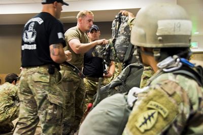 Army Sgt. Daniel Durkee, center, a mechanic assigned to the 10th Special Forces Group, performs a jumpmaster personnel inspection, May 19, 2017, as his wife, Sgt. Angel Durkee, foreground, watches during a static-line jumpmaster course at Fort Carson, Colo. Army photo by Staff Sgt. William Reinier