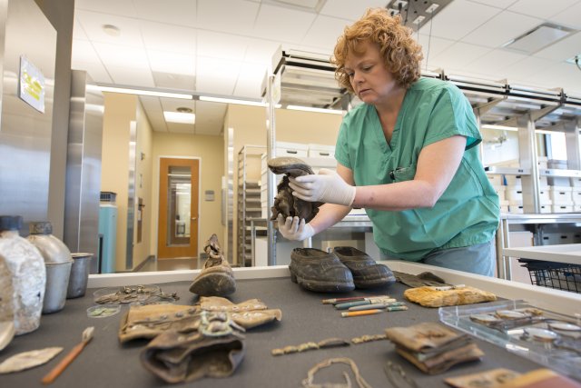 Sgt. 1st Class Jennifer Owen, a morgue NCOIC for the Defense POW/MIA Accounting Agency, examines personal effects that potentially belong to fallen service members inside a laboratory at Joint Base Pearl Harbor-Hickam, Hawaii, March 12, 2018. (Photo Credit: U.S. Army photo by Sean Kimmons)