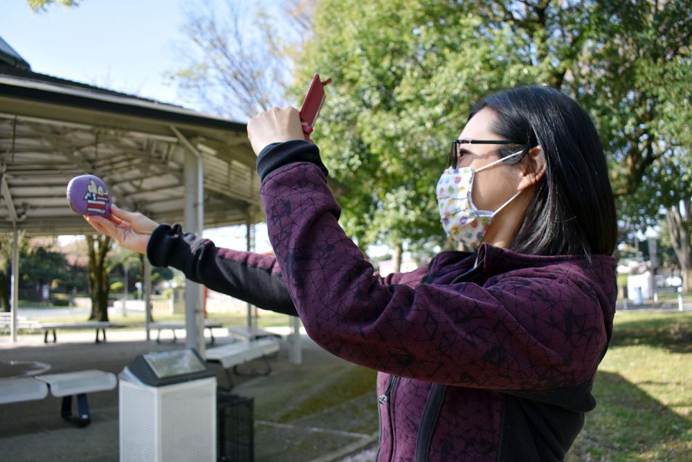 Sabrina Tsai, manager of the Camp Zama Arts and Crafts Center, takes a photo of a painted rock before hiding it for the center’s Easter Rock Hunt at Camp Zama, Japan, April 9. (Photo by Winifred Brown, U.S. Army Garrison Japan)