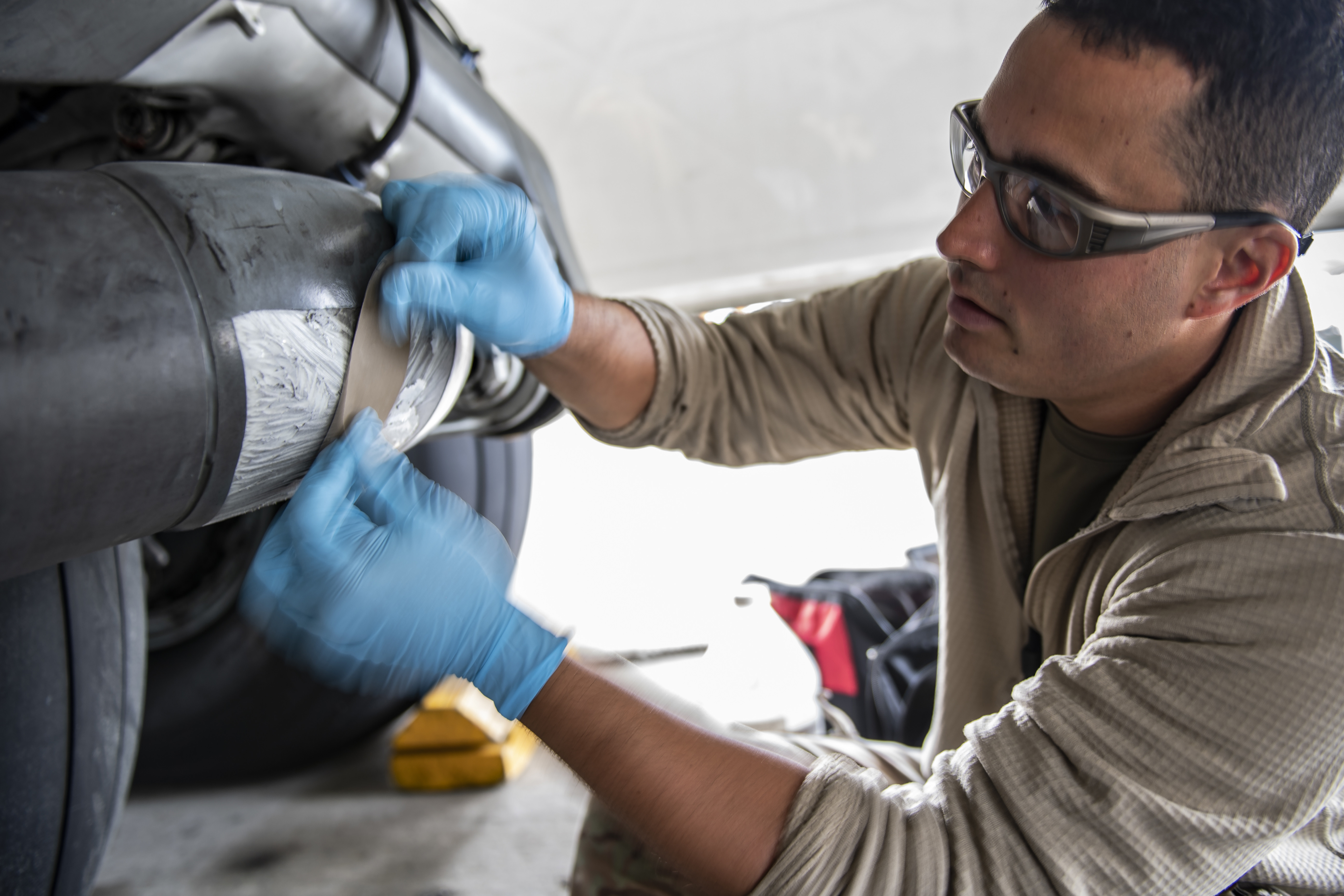 Staff Sgt. James Krobot, 911th Maintenance Squadron aircraft structural maintenance technician, sands down anti-chafing tape on a C-17 Globemaster III main landing gear assembly during a home station check inspection at the Pittsburgh International Airport Air Reserve Station, Pennsylvania, May 18, 2020. Airmen are performing the first ever HSC in Pittsburgh on the flightline due to the travel restrictions in place because of COVID-19 while the new hangar is still under contruction. (U.S. Air Force photo by Joshua J. Seybert)