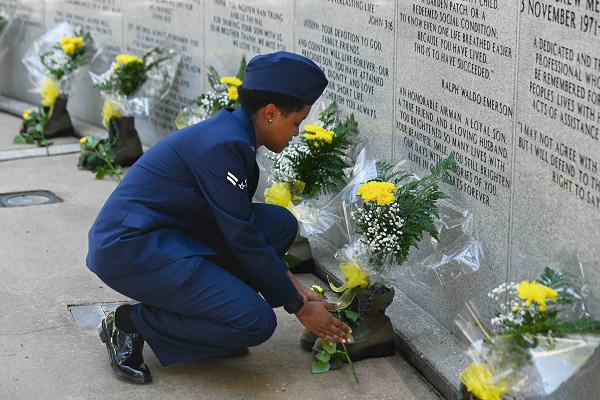 U.S. Air Force Airman 1st Class Bobbie Mills, 60th Fighter Squadron aircrew flight equipment apprentice, places a rose to honor a fallen airman during the Khobar Towers memorial ceremony at Eglin Air Force Base, Florida, June 25, 2024. Placing the flower over the toes of the uniform boots is a tradition that honors the lives lost.  (U.S. Air Force photo by Senior Airman Briana Beavers)