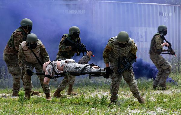 Airmen defend a mannequin on a stretcher during a training exercise at the Tactics and Leadership Nexus training site at Dover Air Force Base, Del., July 11, 2024. During the training, the Airmen used new airsoft rifles to improve the deployment training experience, simulating carrying and firing weapons, while also being safer than using an M-4 with non-lethal training rounds. (U.S. Air Force photo by Airman Liberty Matthews) 