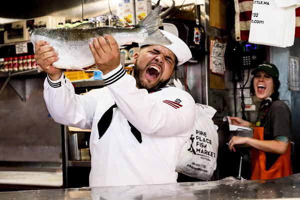 U.S. Navy Gas Turbine Systems Technician (Electrical) Fireman Jaxon Moon, a Sailor aboard the guided missile destroyer USS Sampson (DDG 102), celebrates after catching a fish at Pike Place Market in Seattle during Seattle Seafair Fleet Week July 31, 2024.  Seattle Fleet Week is a time-honored celebration of the sea services and provides an opportunity for the citizens of Washington to meet Sailors, Marines and Coast Guardsmen, as well as witness firsthand the latest capabilities of today’s maritime services. (U.S. Navy photo by Mass Communication Specialist 1st Class Jacob I. Allison)