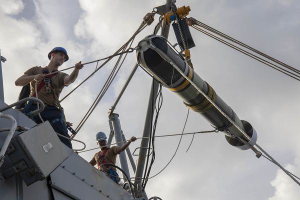 Sonar Technician (Surface) 3rd Class Josiah Kirchofer, left, from Dallas, and Sonar Technician (Surface) 2nd Class Pierre Ducasse, from Los Angeles, hoist an Mark 54 lightweight torpedo onto the aft missile bay from the flight deck of the Arleigh Burke-class guided-missile destroyer USS Spruance (DDG 111). Spruance, assigned to the Abraham Lincoln Carrier Strike Group, is underway conducting routine operations in the U.S. 7th Fleet area of operations. U.S. 7th Fleet is the U.S. Navy’s largest forward-deployed numbered fleet, and routinely interacts and operates with allies and partners in preserving a free and open Indo-Pacific region. (U.S. Navy photo by Mass Communication Specialist Seaman Joey Sitter)                                                 