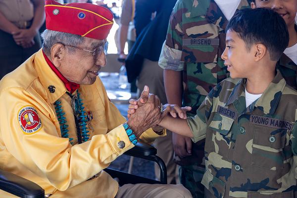 U.S. Marine Corps Navajo Code Talker veteran, Cpl. Peter Macdonald, former Navajo Nation Chairman, engages with members of the Young Marines program during the 2024 Navajo Code Talkers Day event at the Navajo Nation Fairgrounds in Window Rock, Arizona, Aug. 14, 2024. Navajo Code Talkers Day is observed annually to honor the service of Navajo Code Talkers and other Native American veterans. During World War II, the Navajo language was used to create an unbreakable military code. The event included attendees from the Marine Corps, the Young Marines, the Navajo Code Talkers Association, and Navajo Code Talkers and their families. (U.S. Marine Corps photo by Lance Cpl. Erica Stanke)