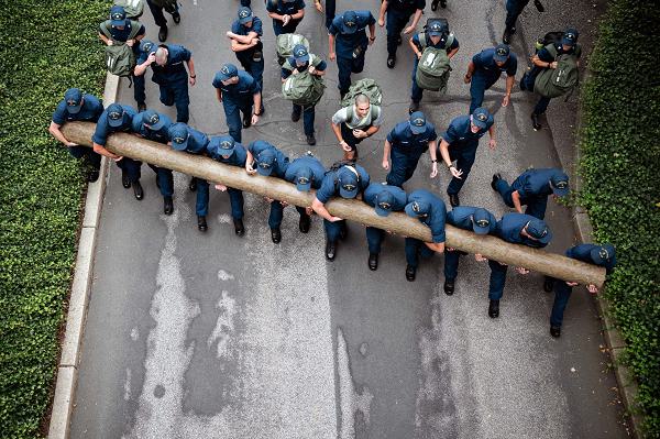 U.S. Coast Guard Cadets carry a log uphill during sea trials at the Academy, New London, Conn., Aug 17, 2024. Sea Trials is a set of daylong exercises that challenges swabs physically and mentally, while also marking the conclusion of the summer training program. (U.S. Coast Guard photo by Petty Officer 3rd Class Matt Thieme.)