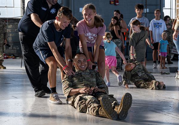 Children of service members assigned to Wright-Patterson Air Force Base move a simulated injured Airman during a Kids Understanding Deployment Operations event at Wright-Patterson AFB, Ohio, Aug. 9, 2024. The KUDOS event is intended to teach children about deployment through simulated age-appropriate deployment activities. (U.S. Air Force photo by Senior Airman Elizabeth Figueroa) 
