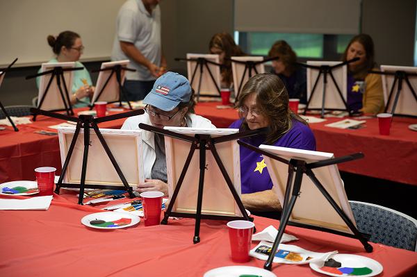 (From Left to Right) Amie Gullifer and Sue VanGiesen paint their canvases during a painting class held during the annual West Virginia National Guard Gold Star Families Weekend Retreat on September 28, 2024 at Camp Dawson, in Kingwood, West Virginia. Since its first congressional designation in 1936, the last Sunday in September has been recognized as “Gold Star Mother’s Day” and in 2012 was declared “Gold Star Mother’s and Family’s Day”. The West Virginia National Guard hosts Gold Star families from West Virginia and Pennsylvania to convene annually at Camp Dawson for three days of fellowship and remembrance. (U.S. Army National Guard Photo by Cdt. Ayden Norcross)