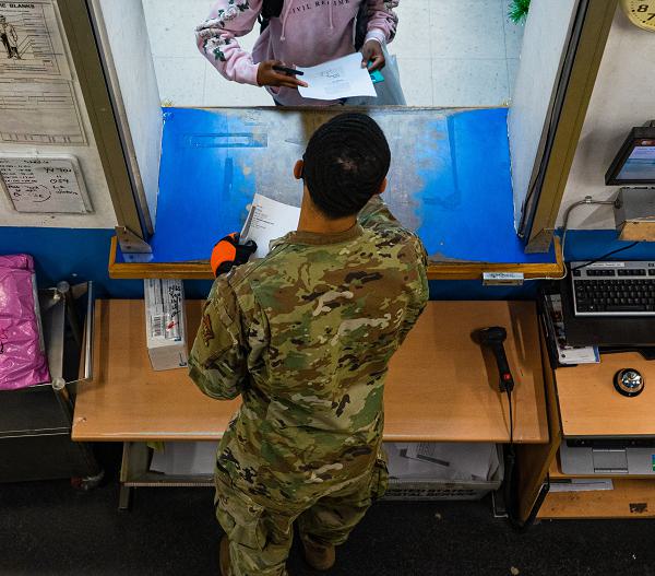 Airman 1st Class Damon Thompson, 51st Force Support Squadron postal clerk, speaks with a customer collecting an oversized package at the Osan Air Base Post Office, Republic of Korea, Dec. 9, 2020.  Thompson commits an additional three or four hours to his normal nine hour postal shift during the holiday season to serve a constant flow of customers.  (U.S. Air Force photo by 1st Lt. Daniel de La Fé)
