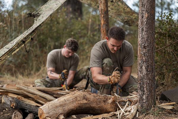 Airman 1st Class Joe Trybus and Airman 1st Class Benathan Deman, 66th Training Squadron Survival, Evasion, Resistance and Escape students, use knives to split wood during a firecraft exercise at Fairchild Air Force Base, Wash., Sept. 17, 2024. Throughout the training pipeline, SERE students are taught techniques to adapt to their surroundings in order to survive. (U.S. Air Force photo by Senior Airman Tiffany Del Oso) 