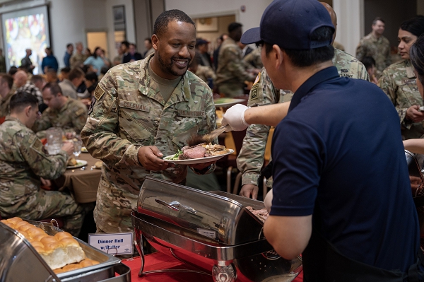 Tech. Sgt. Aaron Coleman, 8th Mission Support Group resource advisor, receives food during the annual Thanksgiving meal hosted by the Korean-American Gunsan Alliance at Kunsan Air Base, Republic of Korea, Nov. 8, 2023. KAGA are representatives of Kunsan AB’s Good Neighbor Program, which was instituted by U.S. Forces Korea to connect U.S. service members to their local community. (U.S. Air Force photo by Capt. Kaylin P. Hankerson)