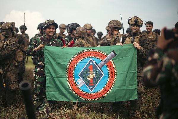 U.S. Marine Corps 1st Sgt. Chris Smith, right, company first sergeant for 2nd Battalion, 7th Marine Regiment, attached to Marine Rotational Force-Southeast Asia, holds a unit flag alongside an Indonesian marine with 10th Marine Infantry Battalion, Indonesian Korps Marinir, after conducting a coastal defense exercise during Keris Marine Exercise (MAREX) 2024 on Kabupaten Lingga, Singkep, Indonesia, Nov. 15, 2024. Keris MAREX is a bilateral exercise conducted by the U.S. Marine Corps and Korps Marinir Republik Indonesia, or Indonesian Marine Corps, to strengthen relationships as military partners and increase interoperability among participating forces in the advancement of a Free and Open Indo-Pacific. MRF-SEA is a rotational unit derived from elements of I Marine Expeditionary Force executing a U.S. Marine Corps Forces, Pacific operational model that involves training events and exchanges with partner military subject matter experts, promotes security goals with Allied and partner nations, and ensures a persistent I MEF presence west of the International Date Line. (U.S. Marine Corps photo by Sgt. Shaina Jupiter)