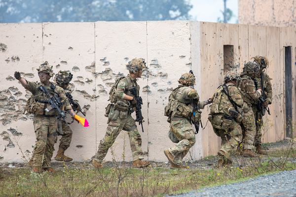 Soldiers from the 4th Battalion, 9th Infantry Regiment, 1st Stryker Brigade Combat Team, 4th Infantry Division, prepare to breach and clear a house during a live fire exercise at the Joint Readiness Training Center 25-02 rotation at Fort Johnson, Louisiana, Nov. 4, 2024. Bright colored flags or markings made on a building can be used to signal other squads that a building has been successfully cleared.