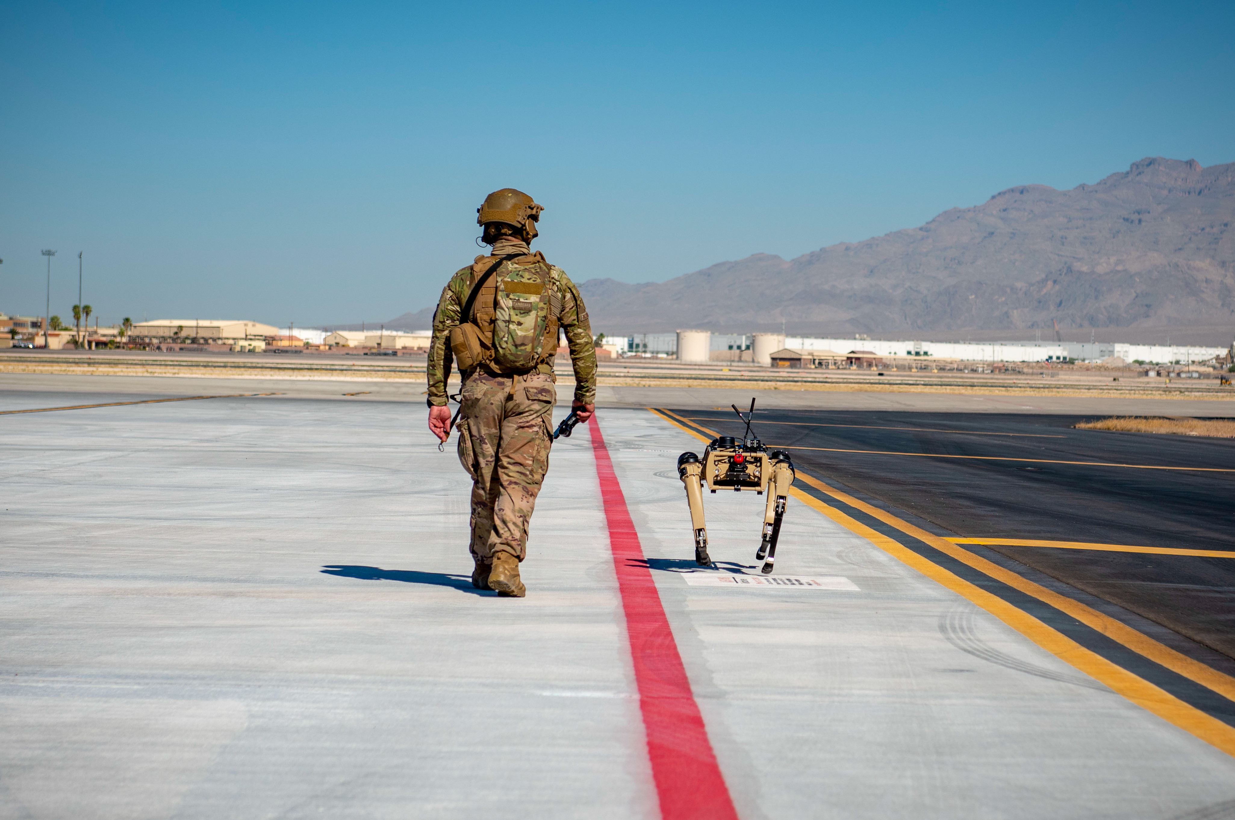 Tech. Sgt. John Rodiguez, 321st Contingency Response Squadron security team, patrols with a Ghost Robotics Vision 60 prototype at a simulated austere base during the Advanced Battle Management System exercise on Nellis Air Force Base, Nev., Sept. 3, 2020. The ABMS is an interconnected battle network - the digital architecture or foundation - which collects, processes and shares data relevant to warfighters in order to make better decisions faster in the kill chain. (photo by Airman First Class Zachary Rufus)