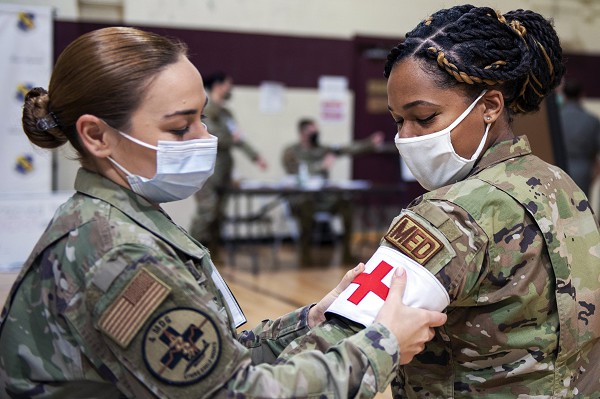 In this photo by Airman 1st Class Kimberly Barrer, Staff Sergeant Maria Monzi with the 4th Medical Readiness Squadron based at Seymour Johnson Air Force Base, North Carolina places a Red Cross arm band on fellow medical technician Staff Sergeant Candice Stafford as they prepare to administer COVID-19 immunizations. The military provides numerous avenues for recruits interested in a medical career.