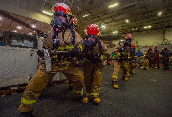 South China Sea (July 27, 2022): In this photo by Mass Communications Specialist Seaman Natasha Chevalier-Losada, sailors fight a simulated fire during damage control drills aboard the Navy’s only forward deployed aircraft carrier, the USS Ronald Reagan. With a population of over 5,000 souls, life aboard is like living in a floating city surrounded by miles of endless ocean views