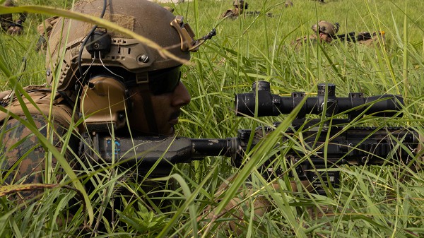 Okinawa, Japan. (August 10, 2022): In this photo by Corporal Christopher Lape, U.S. Marine Corps Lance Corporal Cristobal Denaoseguera, an infantry Marine with Battalion Landing Team 2/5, 31st Marine Expeditionary Unit, holds a defensive position during a helicopter raid exercise on le Shima, Okinawa. During these exercises, Marines train with Japanese Defense Forces to secure an objective and to create forward arming and refueling points. The 31st MEU operates aboard the USS Tripoli Amphibious Ready Group of the U.S. 7th Fleet.