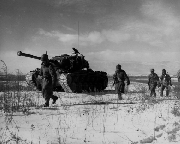 Chosin Reservoir, North Korea. (Oct. 18, 1950): In this classic Korean War photo, members of the U.S. 1st Marine Division, along with their surviving armor, move through Chinese lines in a successful break out from the battle of the Chosin Reservoir. The surprise attack by the Chinese Army surrounded American and South Korean defenders necessitating a brutal battle for survival legendary in the annals of Marine Corps history.