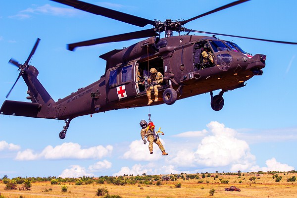 Babadag Training Area, Romania. (September 12, 2022): In this photo by Captain Taylor Chriswell, an HH-60 Medevac helicopter and crew assigned to C Company, 2-227 General Support Aviation Battalion hoist a simulated casualty during personnel recovery training with the United Kingdom in Romania. U.S. troops are relocating to Romania from bases in Germany to shore up NATO’s eastern flank against attacks by the Russians who illegally invaded nearby Ukraine.