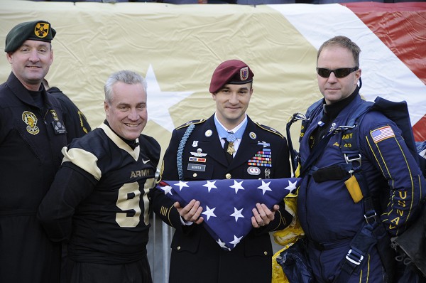 Lincoln Financial Center, PA. (December 11, 2010): Army Staff Sergeant Salvatore “Sal” Giunta is presented the U.S. flag by Navy Parachutist Jim Wood (Right) assisted by members of the famous Army Golden Knights parachute team. SSgt. Giunta was awarded the Medal of Honor for distinguishing himself by acts of gallantry at the risk of his life above and beyond the call of duty in combat operations against enemy forces in Afghanistan.