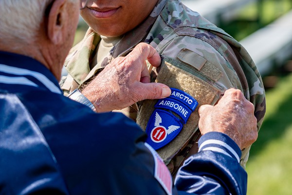 Joint Base Elmendorf-Richardson: (October 5, 2020): In this photo by Senior Airman Patrick Sullivan, Wayne Porter, a U.S. Army veteran who was assigned to the original 11th Airborne Division before its deactivation in 1958, places an 11th Airborne Division shoulder patch on Specialist Jihad Yarber. The presentation was part of a reactivation ceremony for the Army’s newest version of the 11th Airborne that will focus operations on extremely wintry weather and mountainous terrain.