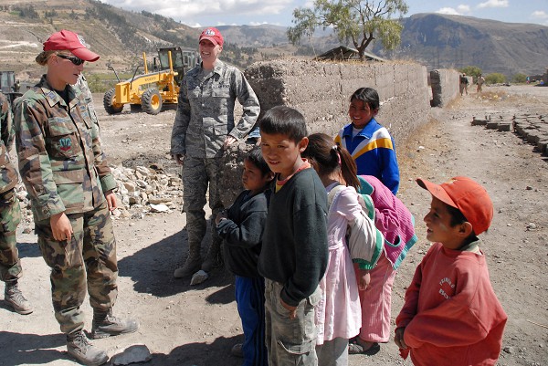 Huamanga, Peru. (October 22, 2022): In this photo by Airmen 1st Class Tracie Forte, Captains Stacy Nimmo and Megan Leitch talk with children during a visit to the construction site for a school being built as part of New Horizons Peru, an event that benefits thousands of Peruvians. Servicemembers from the U.S. Air Force, Army, Marines, and Navy come together to construct schools, clinics, and water wells for Peruvians while building lifelong friendships and comrades.  Captains Nimmo and Leitch hail from the 820th RED HORSE Squadron at Nellis Air Force Base, Nevada.