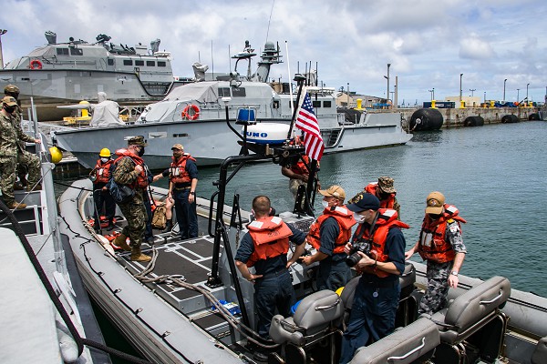 Naval Base Guam (November 2, 2020): In this photo by Lance Corporal Brienna Tuck, command and staff of the 31st Marine Expeditionary Unit ride on a rigid hull inflatable boat from the amphibious assault ship USS America to receive a tour of the Mark VI patrol boat. The Mark VI is one of a long line of shallow water patrol craft used by the Navy for drug interdiction and force protection around the world.